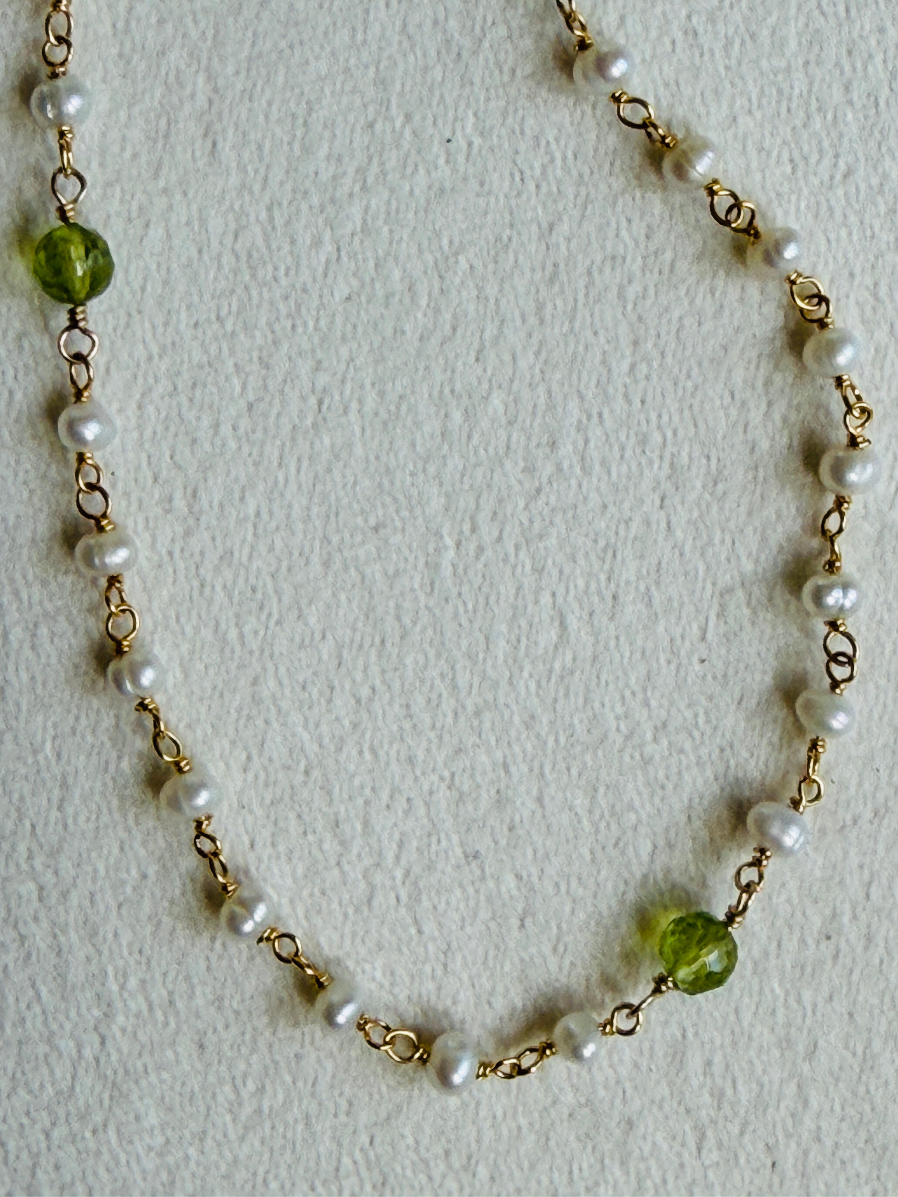 Necklace with pearls and green beads on a light background