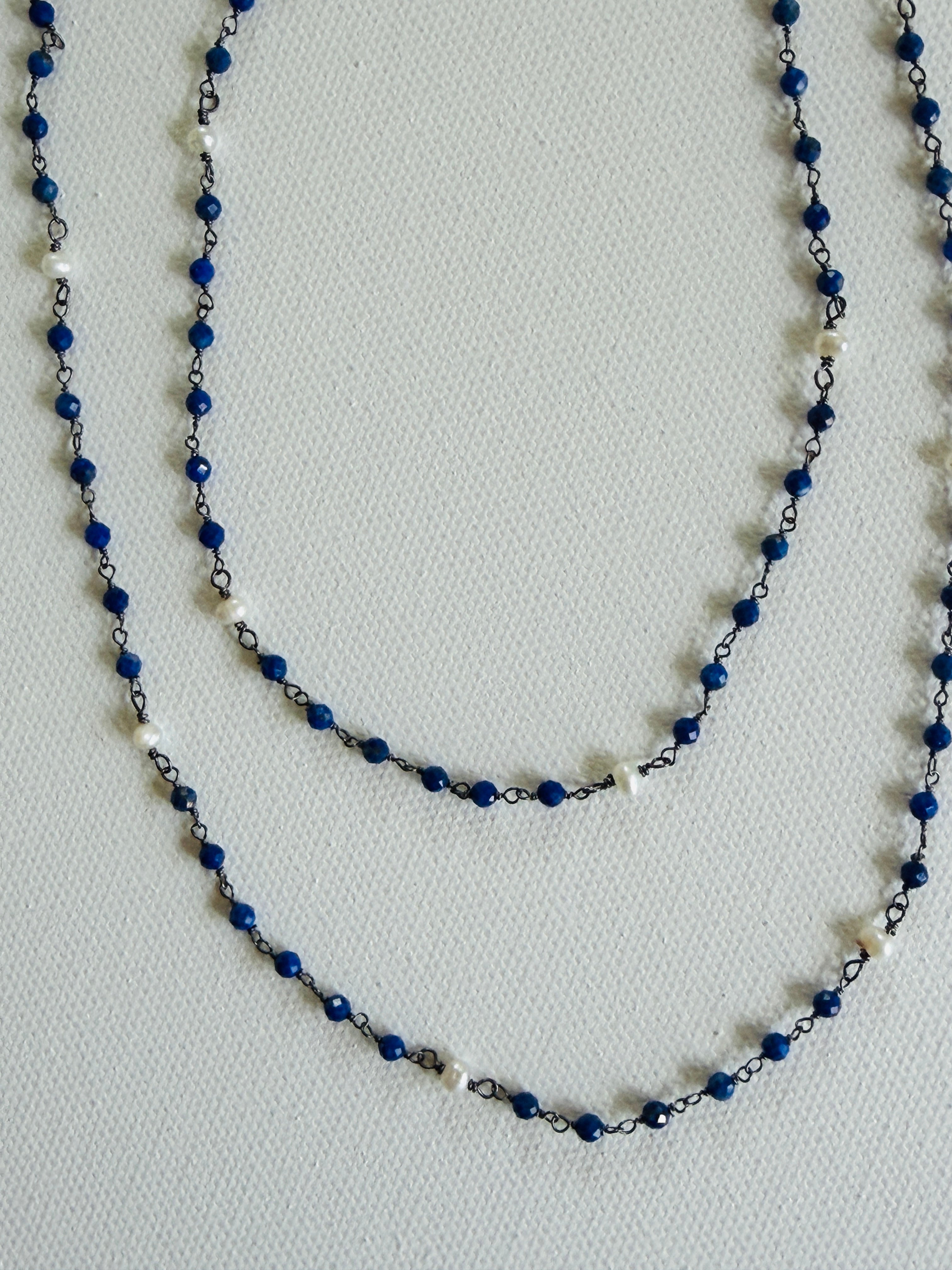 A blue beaded necklace on a light gray background