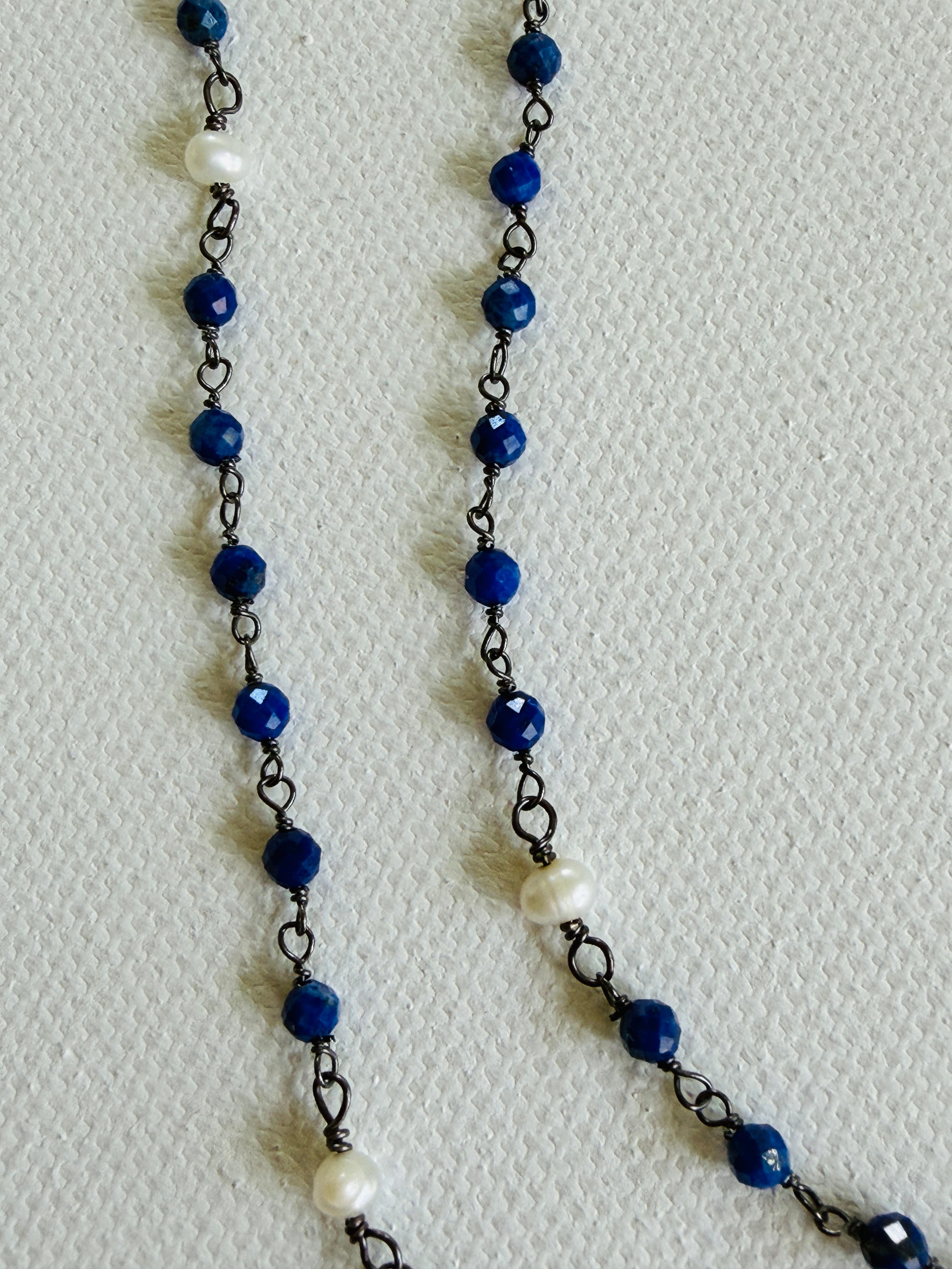 Necklace with blue beads and black chain on a white background
