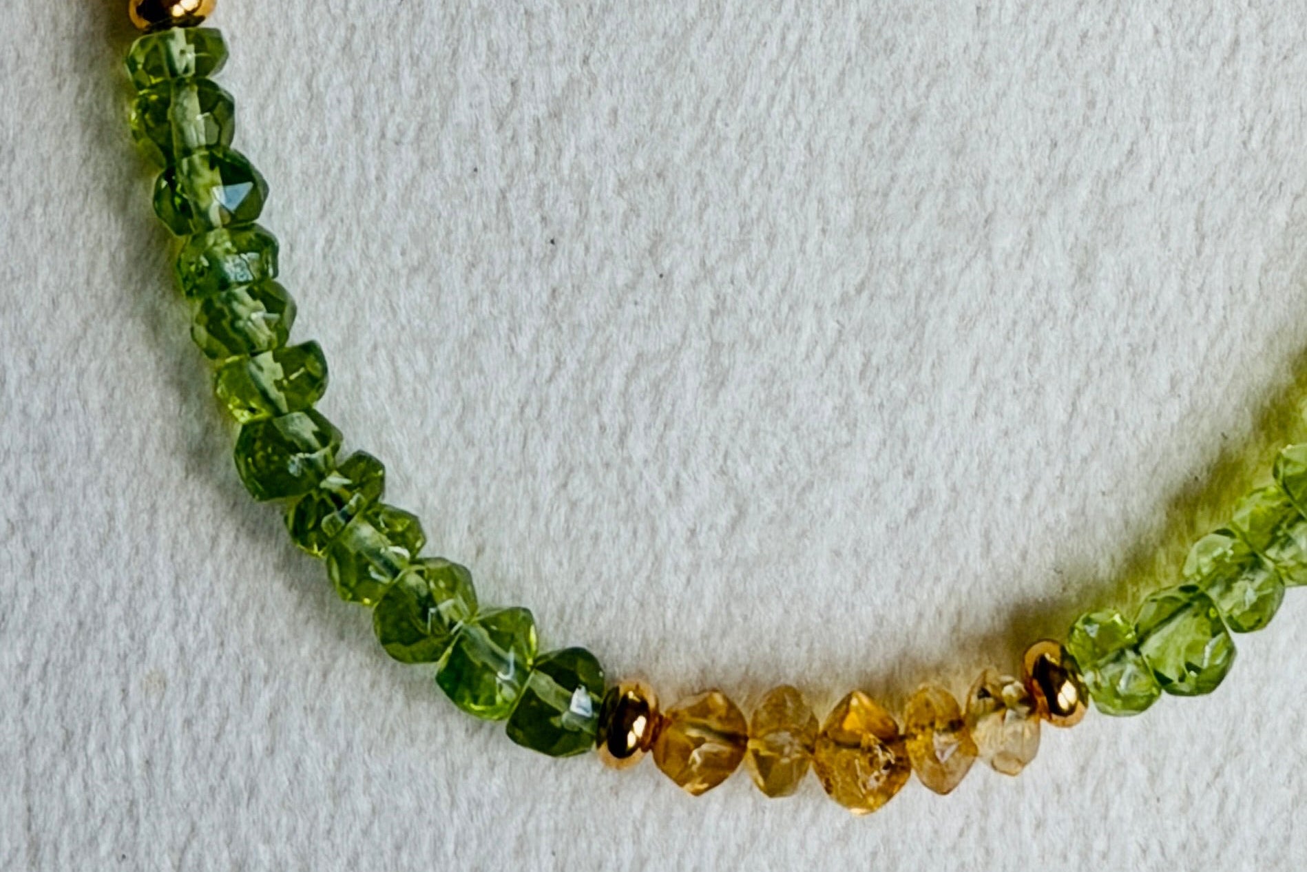 Necklace with green and gold beads on a light gray background